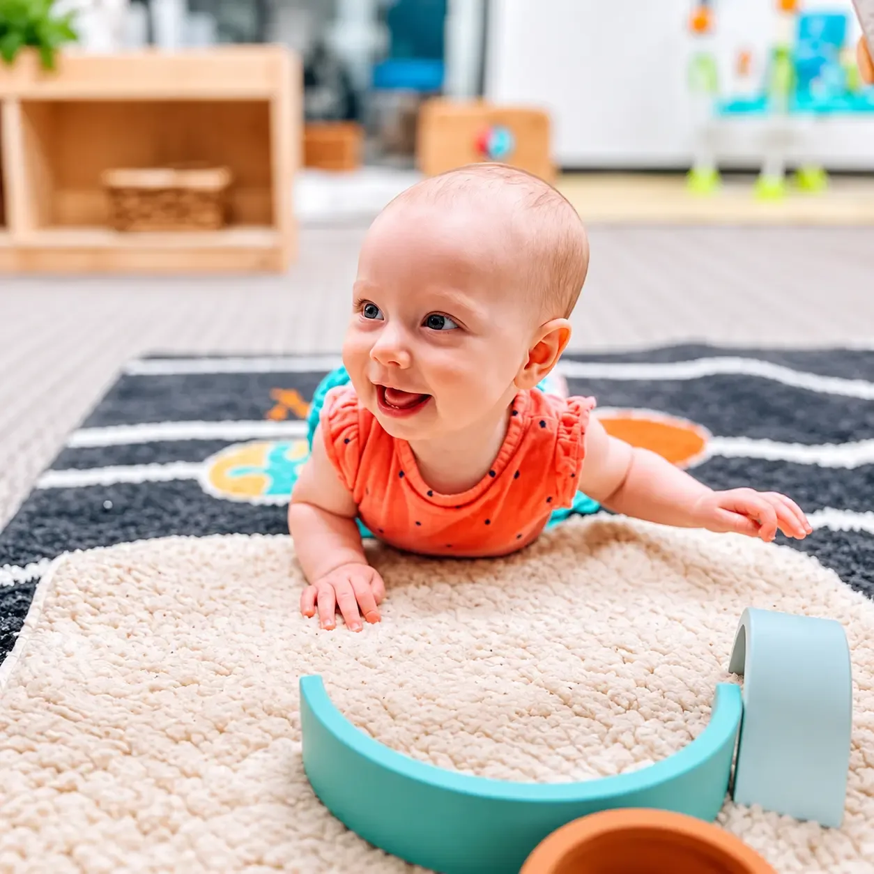 Infant doing tummy time on the classroom rug with wooden toys