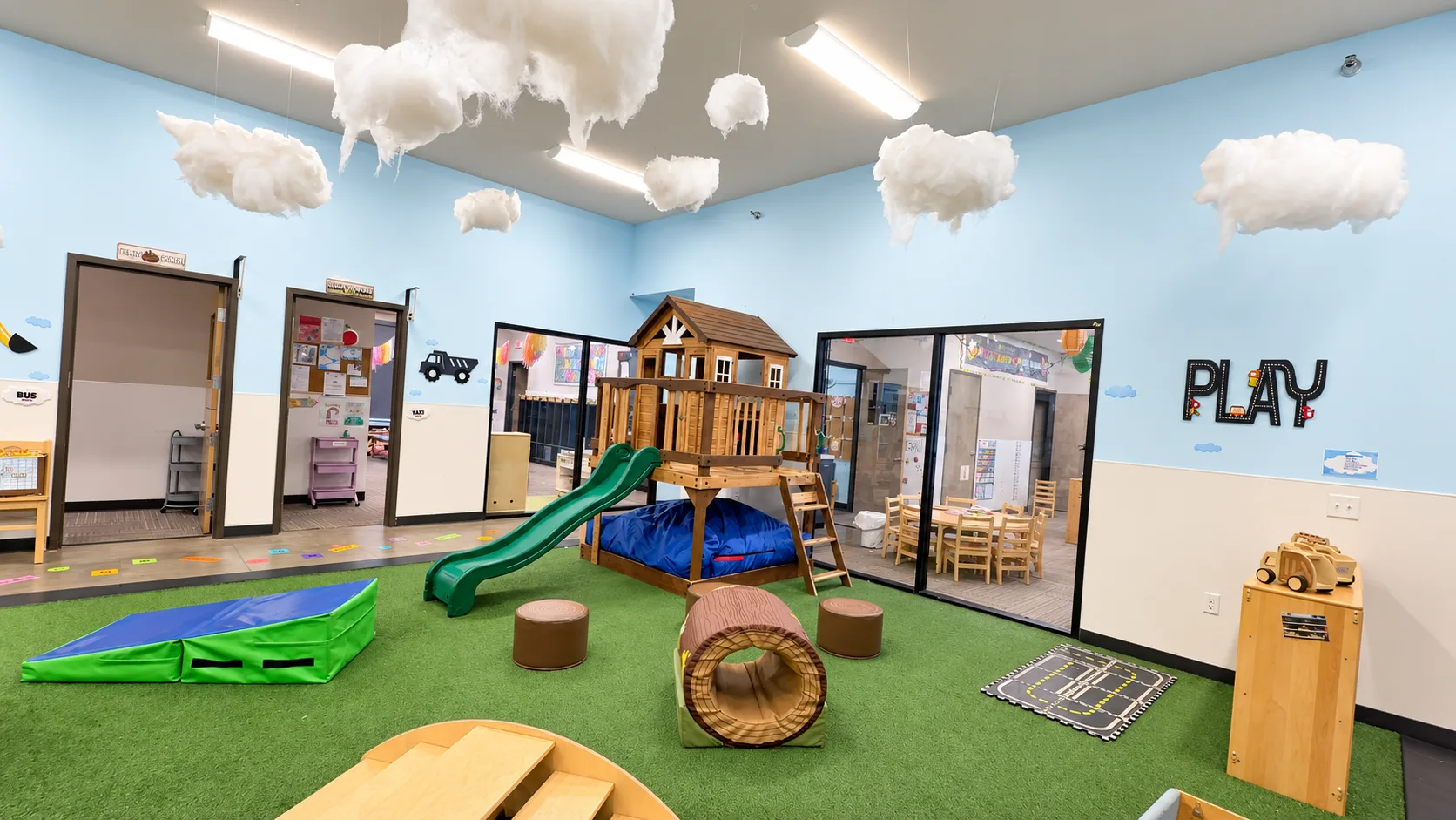 Indoor playground with wooden play structure, green slide, and soft play tunnel