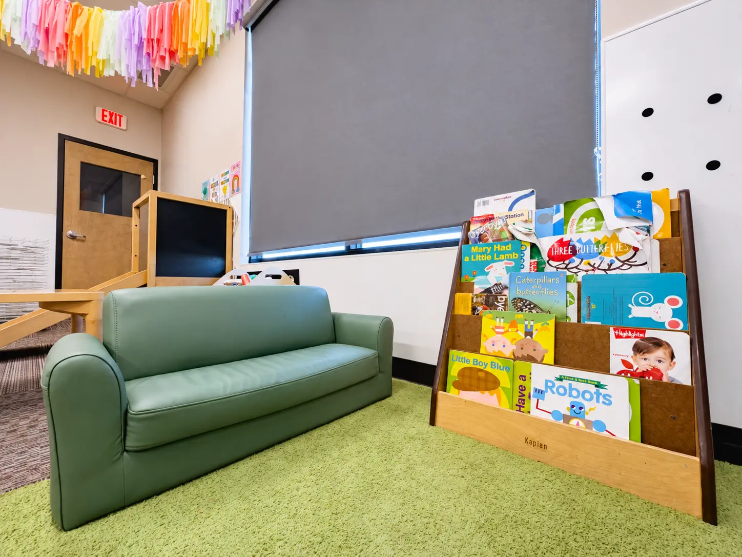 Cozy reading nook with a small green couch and book display